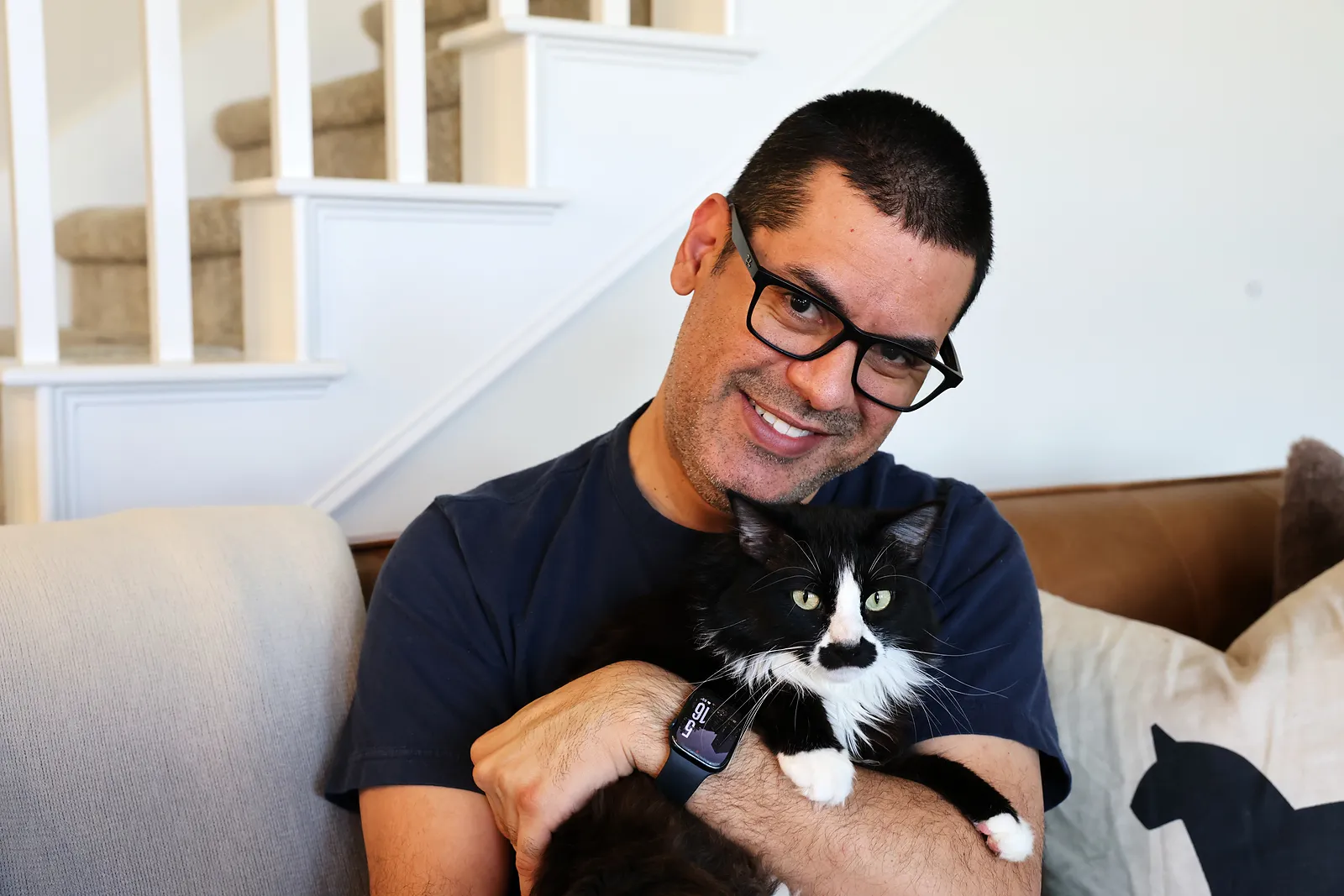 David on the sofa holding his black-and-white cat, Kuro