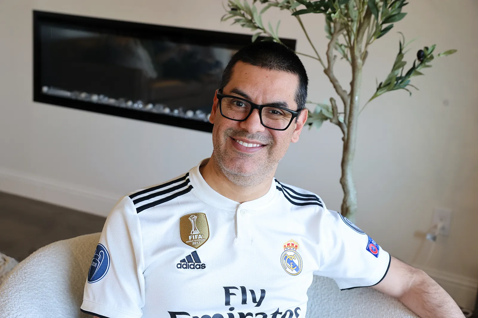 David smiling in a white Real Madrid jersey in his living room